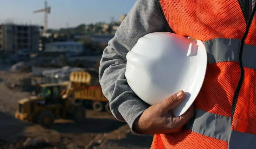un homme qui tient un casque de chantier, sur un chantier