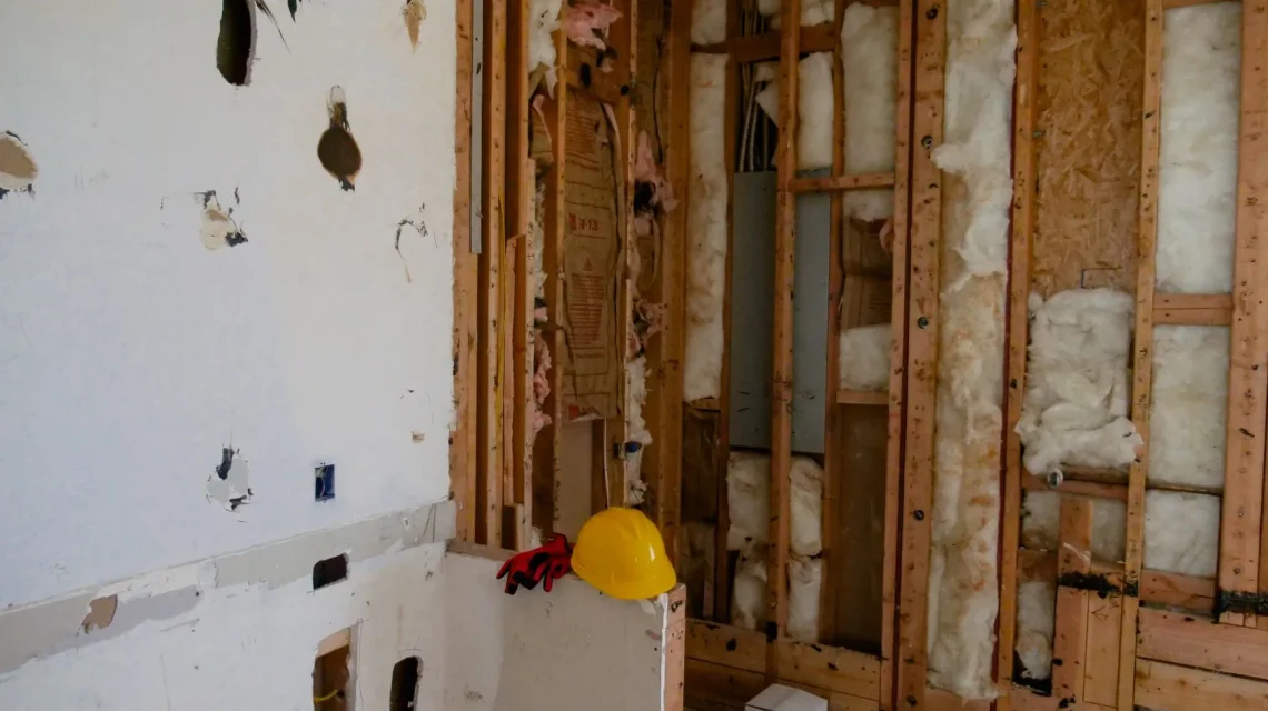 Artisan posant une contre-cloison sur ossature pour l'isolation phonique d'un mur mitoyen