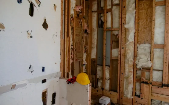 Artisan posant une contre-cloison sur ossature pour l'isolation phonique d'un mur mitoyen