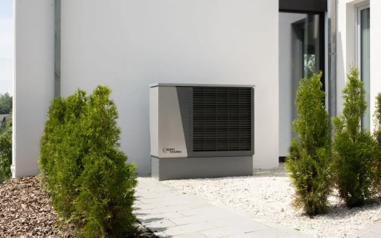 Unité extérieure d'une pompe à chaleur air-eau installée contre la façade d'une maison